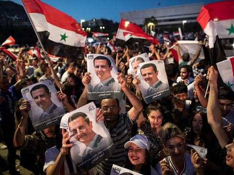Syrian President Bashar Al Assad supporters hold up national flags and pictures of Assad as they celebrate at Omayyad Square, in Damascus, Syria, Thursday, May 27, 2021. 