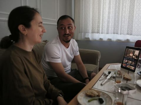 Alparslan Atas, 41, and his wife Gulistan, 38,  laugh over breakfast at their home in Istanbul, while watching on a tablet, Sedat Peker, a Turkish fugitive crime boss on a video, on June 6.