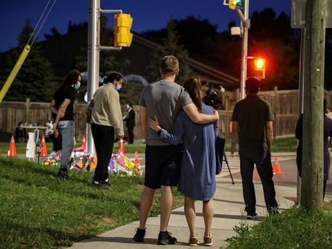 People are seen at a makeshift memorial at the scene where a man driving a pickup truck jumped the curb and ran over a Muslim family in what police say was a deliberately targeted anti-Islamic attack 