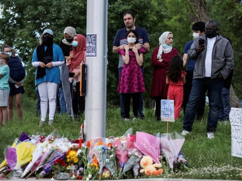 People gather at a makeshift memorial at the fatal crime scene where a man driving a pickup truck jumped the curb and ran over a Muslim family in what police say was a deliberately targeted anti-Islamic hate crime, in London, Ontario. 