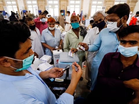 Residents with their registration cards gather at a counter to receive a dose of vaccine at a vaccination centre in Karachi, on June 9, 2021..