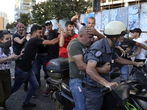 Anti-government protesters hit a member of police intelligence after they saw him taking pictures of protesters in Beirut on Sunday, June 6, 2021. They were protesting against the political leadership they blame for the economic and financial crisis.