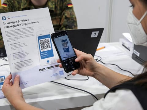 A visitor uses CovPass, Germany's new vaccination passport smartphone app, to scan a QR code after being inoculated at a COVID-19 vaccination center in the Erika-Hess ice rink stadium in Berlin, Germany, on Friday, June 11, 2021. 