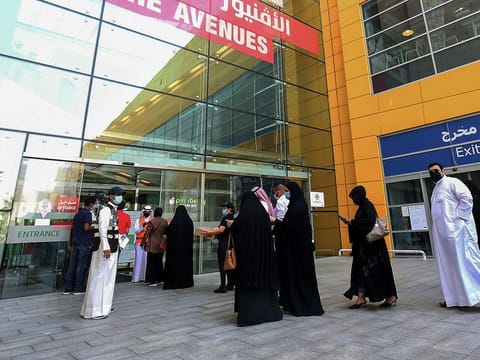 Kuwaiti employees supervise as mall workers verify their vaccination certificates before allowing entry to The Avenues Mall in Kuwait City. 