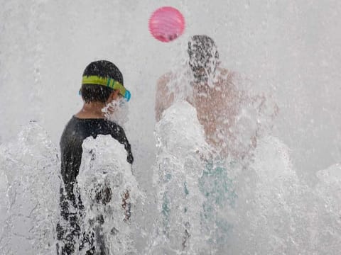 Children play in a riverfront water fountain during a heatwave in Portland, Oregon, U.S., on Saturday, June 26, 2021. Record heat is set to bear down on the Pacific Northwest, threatening fresh strains on regional power and water supplies and dragging down air quality through next week. 