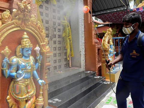 A worker sanitizes a temple premise as the Government allows temples to reopen, in Bengaluru. 