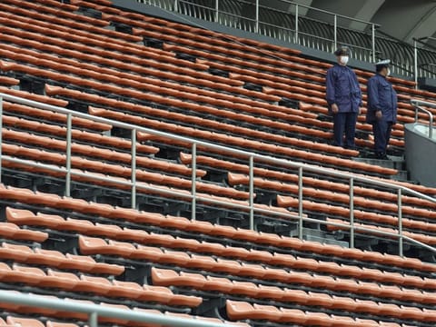 Police officers stand guard at empty seats of the grandstand during the unveiling ceremony for Olympic Flame of the Tokyo 2020 Olympic torch relay at Komazawa Olympic Park, Friday, July 9, 2021, in Tokyo. Komazawa Olympic Park, where the flame unveiling ceremony took place, was used as one of the venues during the previous Tokyo Olympics held in 1964.