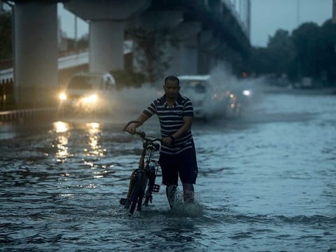 A man pushes his bicycle through a flooded street after heavy rain in Jammu, India, Monday, July 26, 2021. India's monsoon season runs from June to September. 