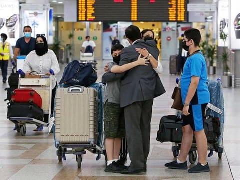 A man greets his family upon their arrival at Kuwait international airport on August 1, 2021, as the authorities allowed entry for fully vaccinated expats. 