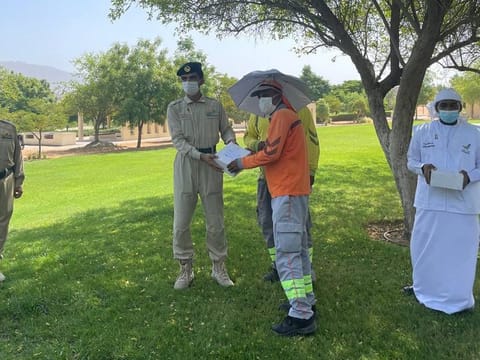 Dubai Police, Spirit of the Union volunteers distribute meals and umbrella hats to workers in Hatta
