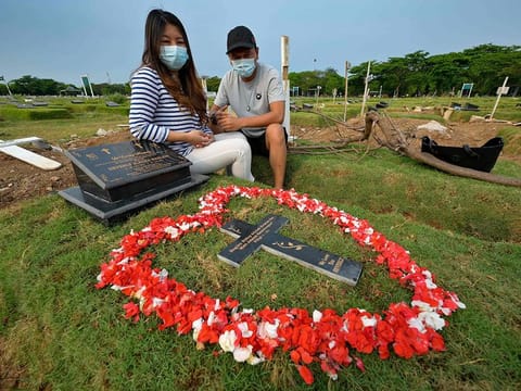 Tirsa Manitik, left, and Erik Alexander visiting the grave of their baby who tested positive for COVID-19 coronavirus before she died, at the Tegal Alur cemetery in Jakarta.