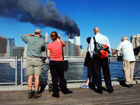 In this file photo pedestrians standing on the Brooklyn waterfront look across the East River towards the burning twin towers of the World Trade Center in lower Manhattan, New York on September 11, 2001.  