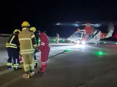 NSRC helicopter on standby while the patient is carried to it for transport to hospital