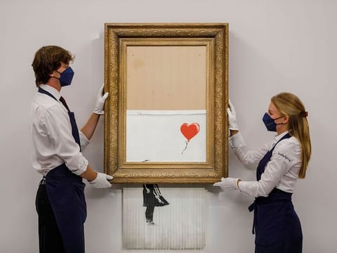 In this handout photo provided by Sotheby's Auction House, the auction for Banksy's "Love is the Bin" takes place in London, Thursday, Oct. 14, 2021. 