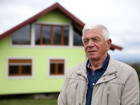 Vojin Kusic poses for a photo in front of his rotating house in Srbac, Bosnia and Herzegovina.