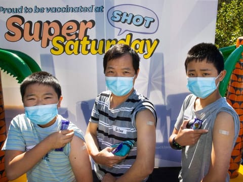 Johnson, left, Bailou and Benson, right, Su of Auckland show their bandaids after receiving their vaccination in Auckland on October 16, 2021. 