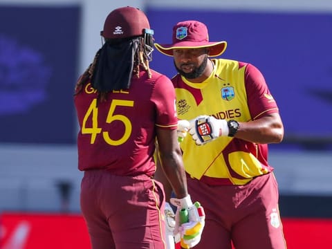 West Indies' captain Kieron Pollard talks to teammate Chris Gayle during the Twenty20 World Cup cricket match against South Africa in Dubai, UAE, on October 26, 2021.