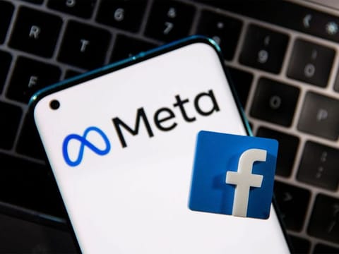  A smartphone with Meta logo and a 3D printed Facebook logo is placed on a laptop keyboard in this illustration.