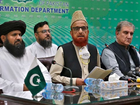 Pakistan's Foreign Minister Shah Mahmood Qureshi, right, and top religious leader Mufti Muneebur Rehman, centre, who helped negotiate an end to a protest march by Islamists, give a press conference, in Islamabad, Pakistan, Sunday, Oct. 31, 2021. 
