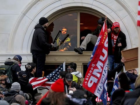 A mob of supporters of then-U.S. President Donald Trump climb through a window they broke as they storm the U.S. Capitol Building in Washington, U.S., January 6, 2021.