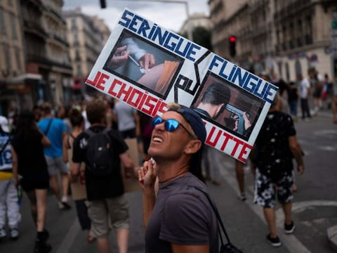 A protester marches with a sign reading in French "syringe or gun" during an anti-lockdown demonstration in Marseille, southern France in a file picture.