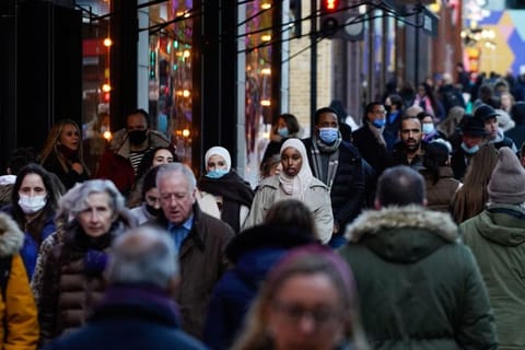 Shoppers walk along Oxford Street in central London on December 10, 2021. The UK government will from Monday tighten virus restrictions in England as Omicron variant cases surge, including guidance to work from home and mandatory COVID passports.  