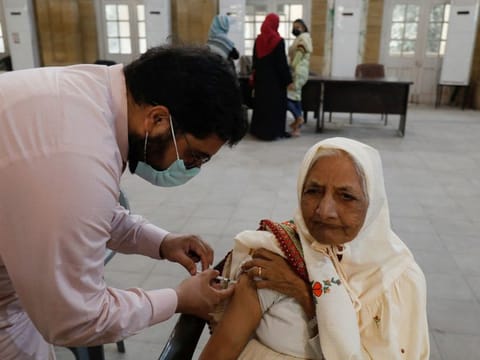 A woman receives a dose of COVID-19 booster vaccine in Karachi, on December 13, 2021.  Among the cities whose eligible populations are largely vaccinated against COVID-19, Islamabad stands first as according to the official data more than 90 per cent of its eligible citizens have been partially and 75 per cent fully vaccinated against COVID-19.