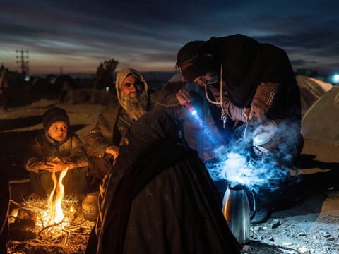 A family prepares tea outside the Directorate of Disaster office where they are camped, in Herat, Afghanistan, on November 29, 2021. Pakistan is rallying Muslim countries to help Afghanistan stave off an economic and humanitarian disaster while also cajoling the neighbouring country's new Taliban rulers into concessions to soften their image abroad. 