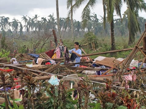 This photo taken on December 18, 2021 and received on December 19 from the Philippine Coast Guard (PCG) shows a resident drying her clothes on the ruins of a home in Del Carmen town in Surigao del Norte province, days after Super Typhoon Rai devastated the province. 