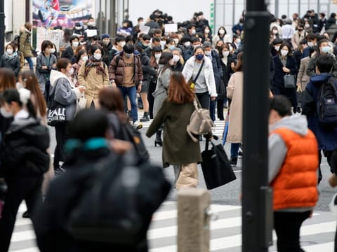 People walk along a pedestrian crossing at Shibuya district on December 17, 2021, in Tokyo.  