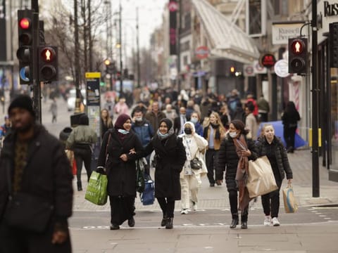 Shoppers on Oxford Street in central London on December 24, 2021. The number of people visiting London's major shopping district was down by almost a fifth on the last weekend before Christmas compared with pre-pandemic levels, a further sign of the toll the spread of the omicron variant is taking on beleaguered UK stores.  