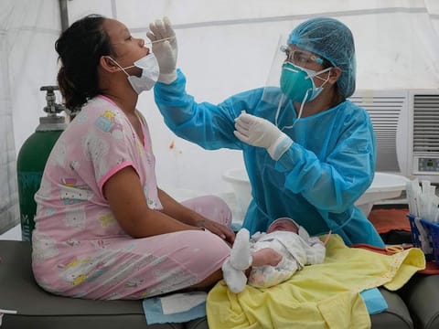 File photo shows medical frontliner Erika Alvarado conducting a COVID-19 test on a patient who just delivered a baby outside a hospital in Manila, Philippines .