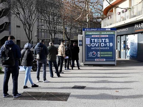 People queue outside a pharmacy to receive COVID-19 antigen tests on January 10, 2022 in Marseille, southern France, as cases soar in Europe.  