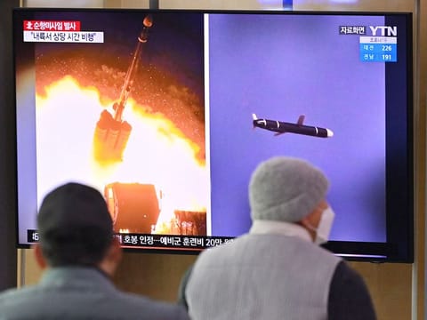 People watch a television screen showing a news broadcast with file footage of a North Korean missile test, at a railway station in Seoul on January 25, 2022. 