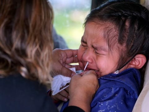 Sophie Gazmin, 4, being tested  for COVID-19 by her mother Eligiia Parra at a No Cost COVID-19 Drive-Through testing provided the GUARDaHEART Foundation for the City of Whittier community and the surrounding areas at the Guirado Park in Whittier, California.