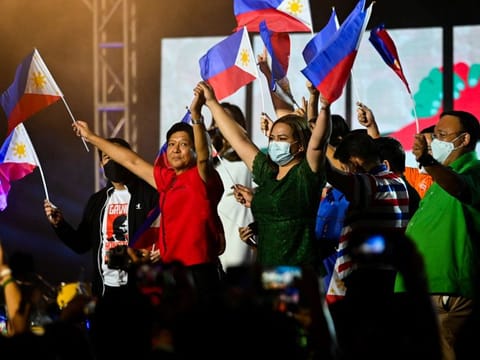 Philippine presidential candidate Ferdinand Marcos Jr., son of late dictator Ferdinand Marcos, and vice-presidential candidate Sara Duterte-Carpio, daughter of Philippine President Rodrigo Duterte, raise their hands as they hold flags, during the first day of campaign period for the 2022 presidential election, at the Philippine Arena, in Bulacan province, on February 8, 2022.  