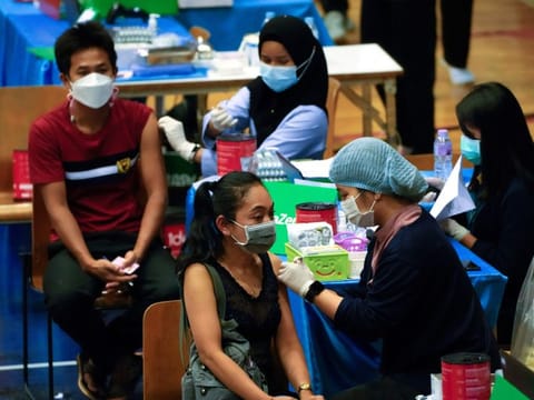 A health worker administers a dose of the AstraZeneca COVID-19 vaccine to a woman in Bangkok, Thailand, on February 23, 2022.  