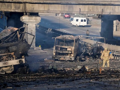 A Ukrainian soldier walks past debris of a burning military truck, on a street in Kyiv, Ukraine, on Saturday, February 26, 2022. 