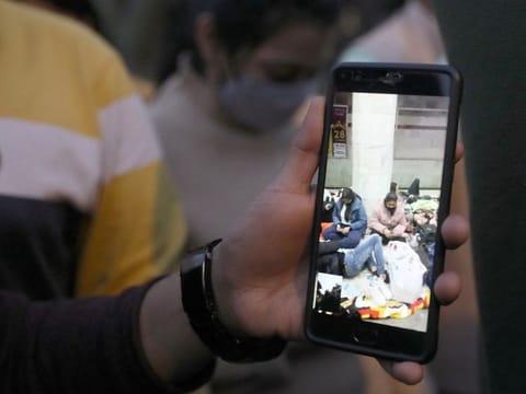 A man shows his mobile phone on which he is on a video call with Indian students stuck in Ukraine, as family and friends of the students demand the Indian Government to evacuate the stranded students, near the Russian embassy in New Delhi, on February 25, 2022. 