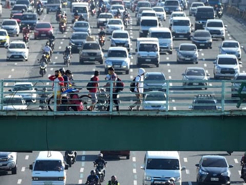 People walk as traffic builds up as the government places the capital on the lowest rung of a five-step pandemic alert system on Tuesday, March 1, 2022, in Quezon city, Philippines.