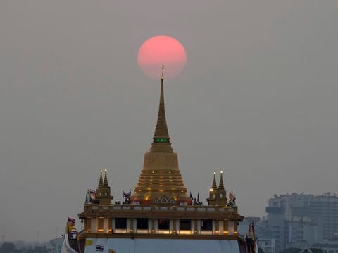 The sun sets behind the golden mount temple in Bangkok, Thailand.