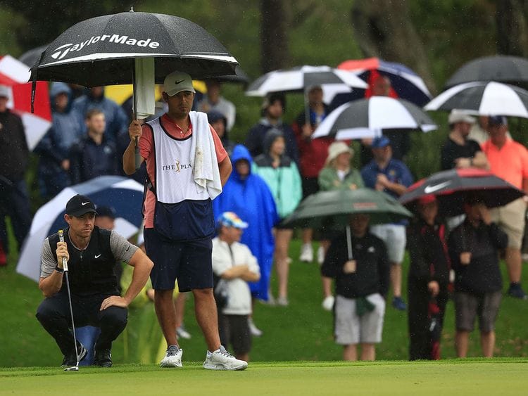 Rory McIlroy lines up a putt in pouring rain at the Players Championship 