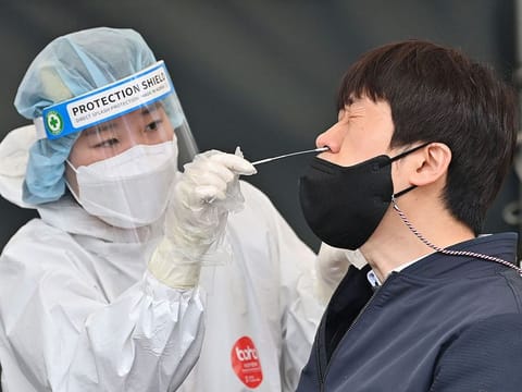 A medical worker (left) takes a nasal swab sample from a man at a COVID-19 testing centre in Seoul on March 17, 2022, after South Korea's daily infections rose sharply to hit a new high of over 600,000. 