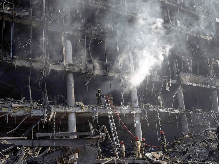 Firefighters try to extinguish a fire amid the destruction caused after shelling of a shopping center, in Kyiv.
