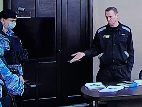 Russian opposition leader Alexei Navalny, right, gestures via a video link provided by the Russian Federal Penitentiary Service, as he speaks with Penitentiary Service officers during a court session in Pokrov, Vladimir region, about 100 kilometers (62 miles) east of Moscow, on March 22, 2022.  