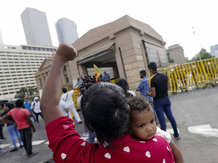 A woman carries her baby and shouts slogans