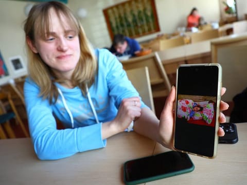 Viktoria Naumenko, a 39-year-old war historian from Kharkiv, shows a picture of her on a mobile phone, as she rested in the cellar of her apartment building used as a bomb shelter, while sitting in a dining room at the International Youth Meeting Center, around two kilometres away from the former Auschwitz-Birkenau death camp, where she is provided with temporary accommodation, in Oswiecim, Poland, March 13, 2022.  