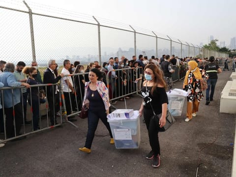 Lebanese civil servants assigned to run polling stations carry ballot boxes in the capital Beirut on May 14, 2022, on the eve of the parliamentary elections.  