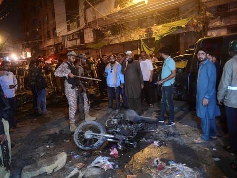 Security officials inspect the site after a bomb blast in Karachi on May 16, 2022, that killed one and injured nine, police said. 