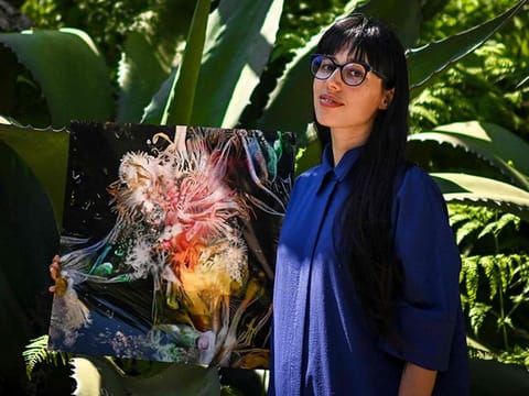 Argentinian artist Sofia Crespo holds one of her works at the Estrela garden in Lisbon.